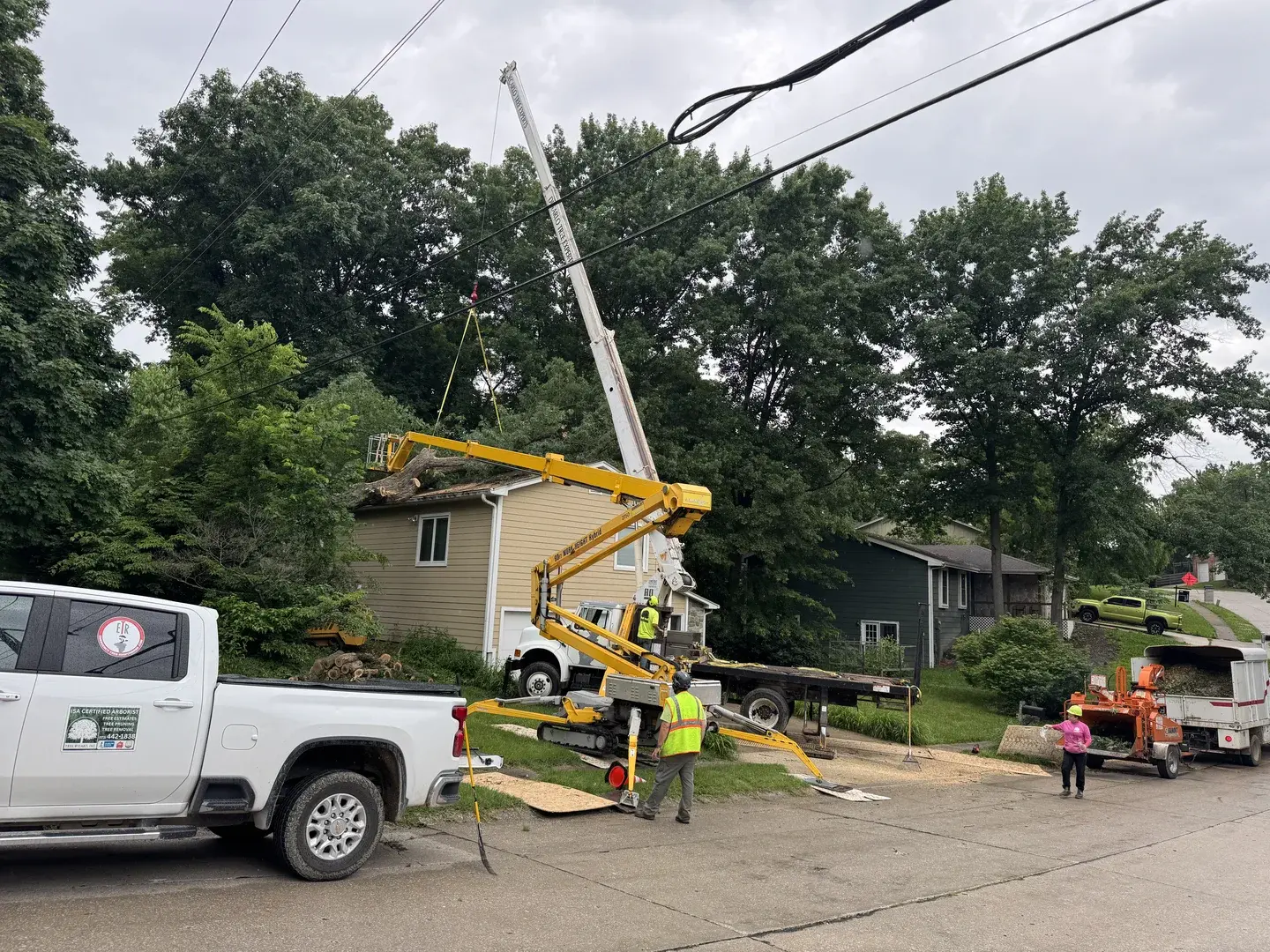 Crane lifting a large tree section away from a home